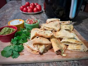 Stack of quesadillas on board with toppings arrayed beside them