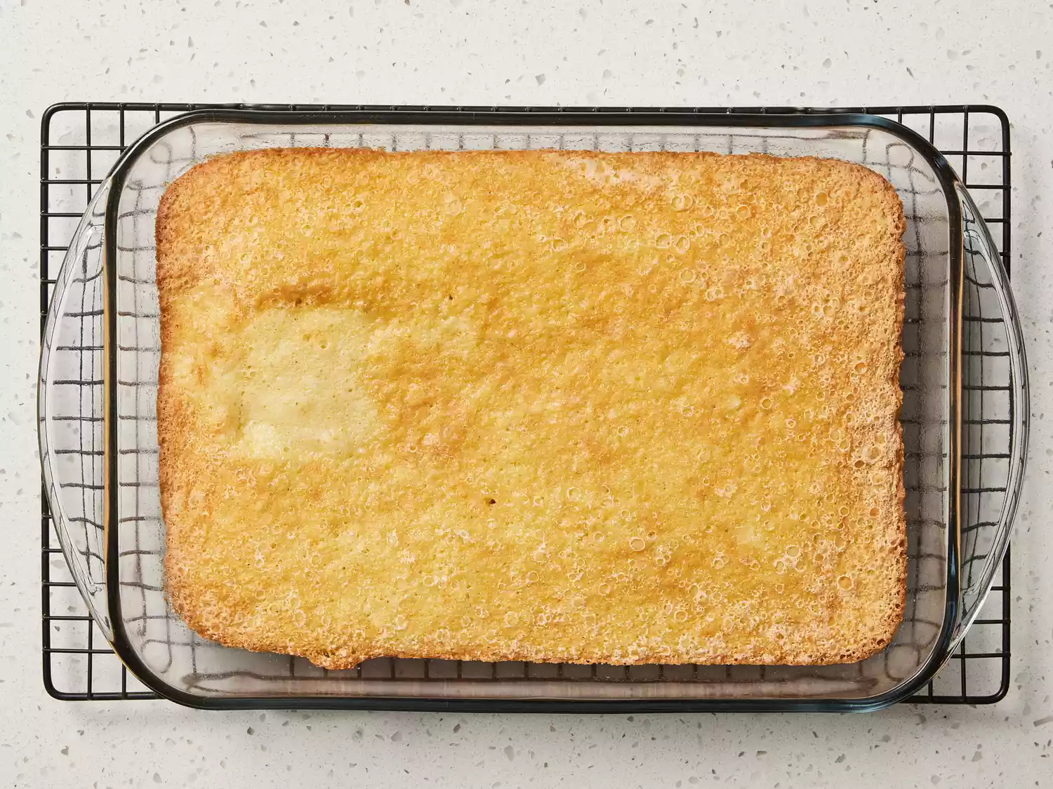 Baked cake in a glass baking dish on a wire cooling rack