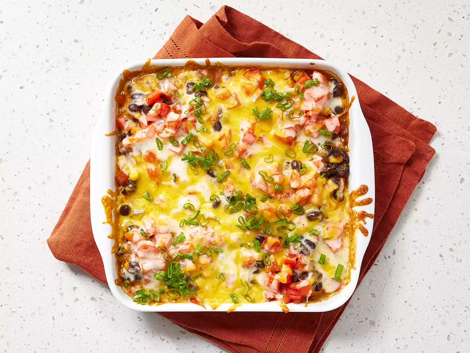 Black Bean Casserole topped chopped green onions in a white casserole dish 