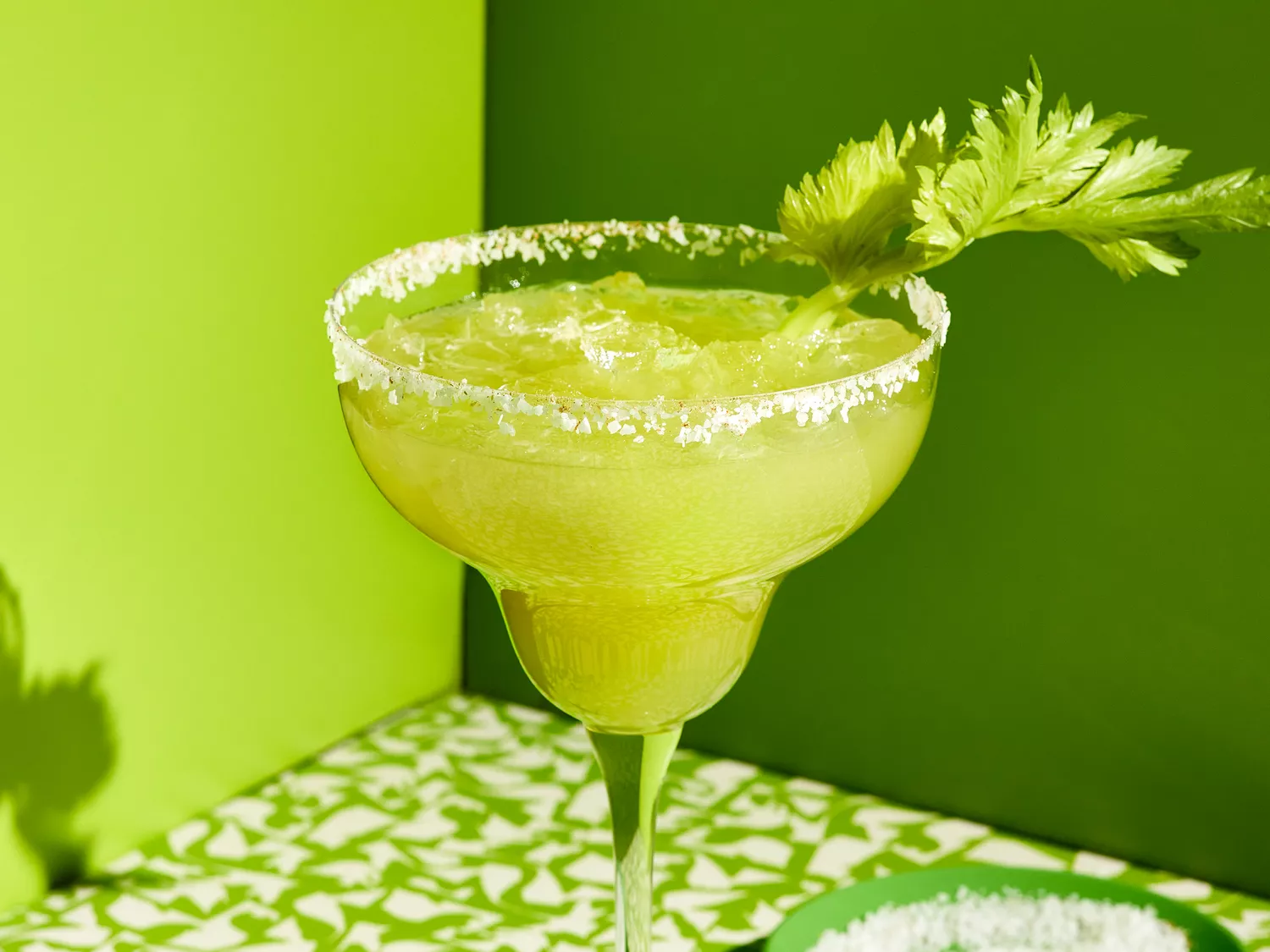 Celery margarita garnished with salt on the rim and celery leaves