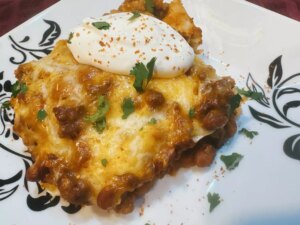 Enchilada casserole served on plate with cilantro and sour cream