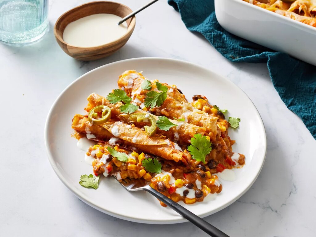 Taquito casserole garnished with pickled jalapeÃ±os and fresh herbs on a plate with a fork