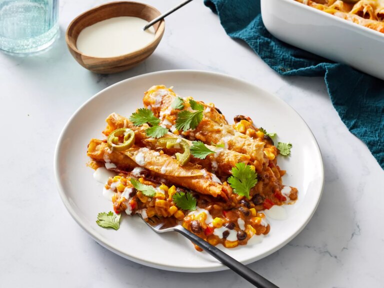 Taquito casserole garnished with pickled jalapeÃ±os and fresh herbs on a plate with a fork