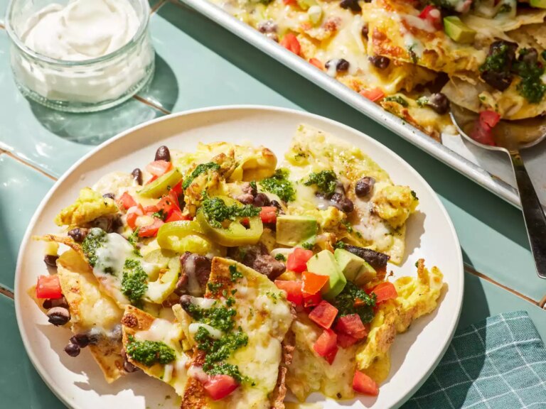 Breakfast nachos garnished with chimichurri and picked jalapeÃ±os on a plate