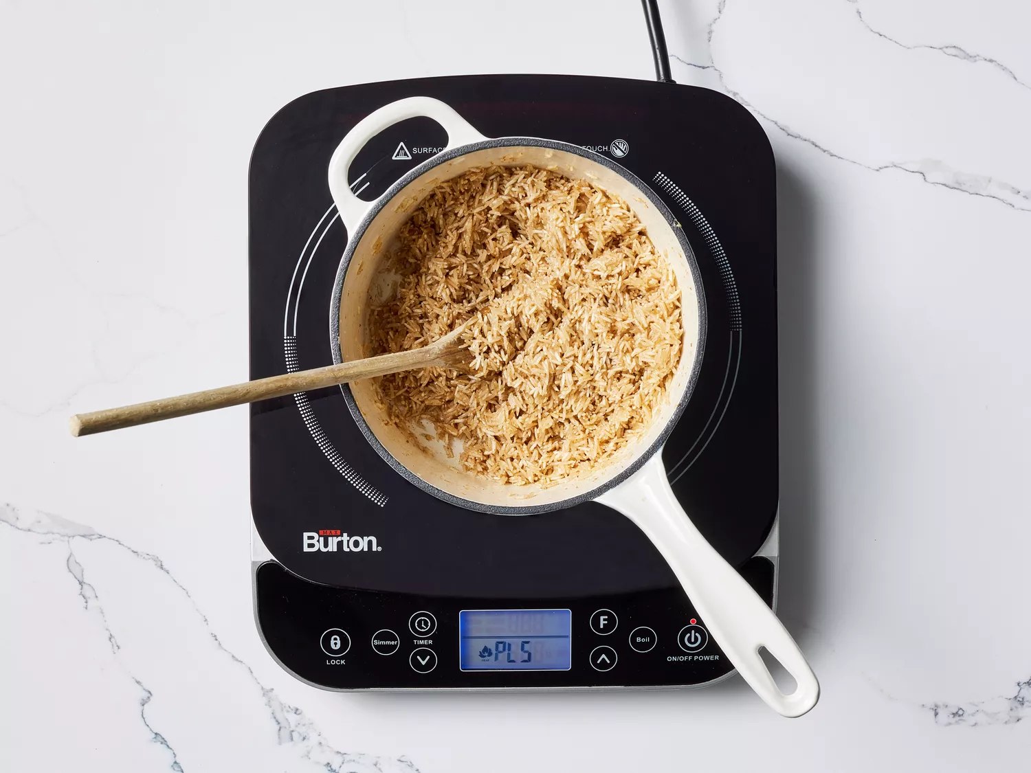Seasoned rice in a pot with with a wooden spoon, on a burner 