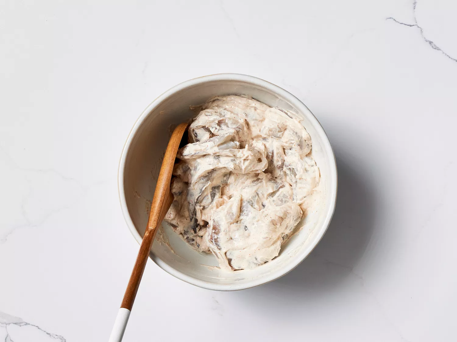 Shrimp with yogurt and spice mixture in a bowl with a spoon 