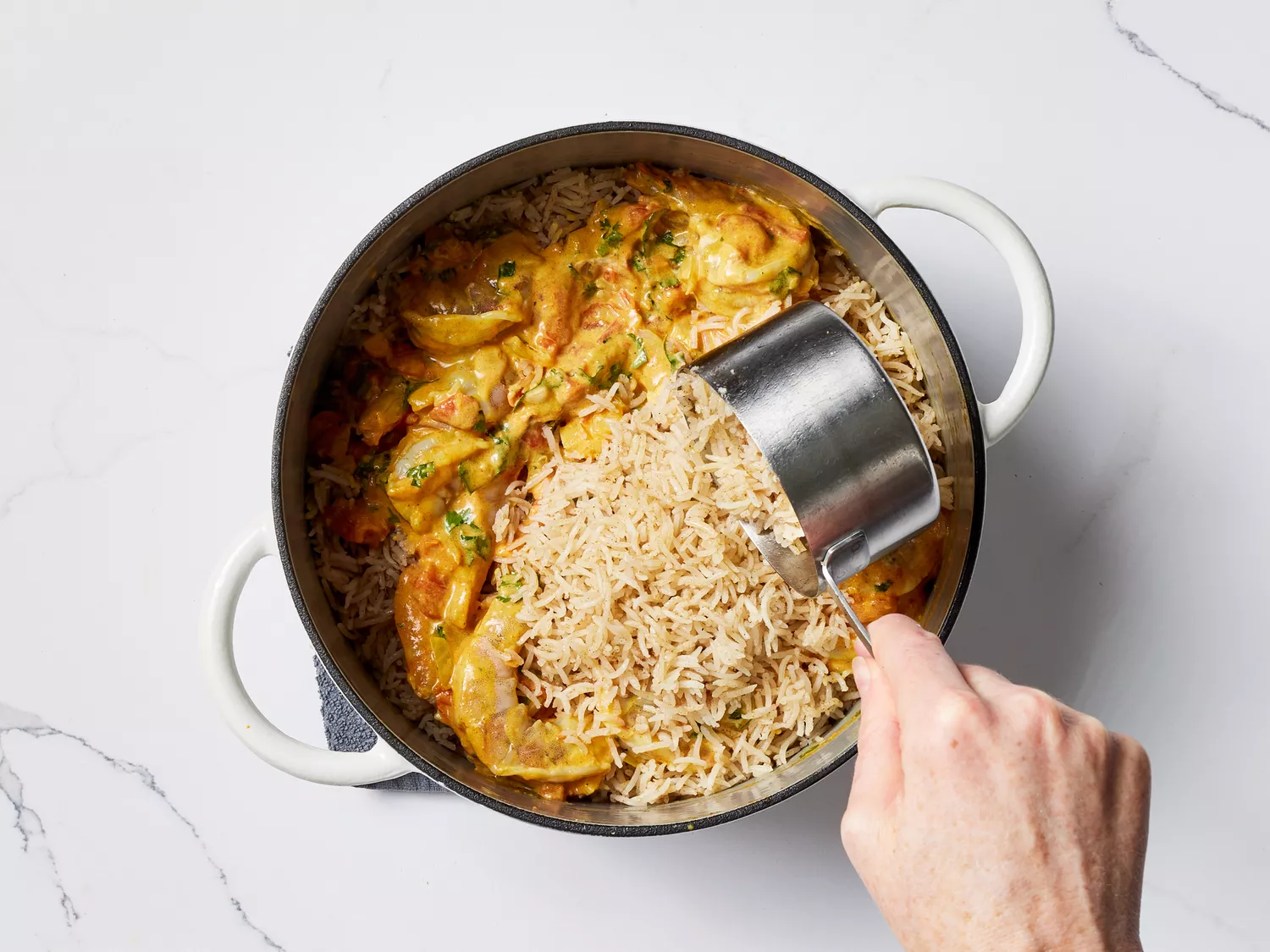 Rice poured over the Shrimp Biryani in a pot 