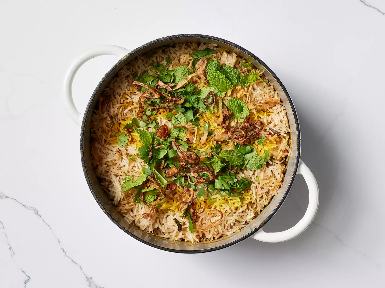 Shrimp Biryani garnished with fresh herbs and fried onions in a pan