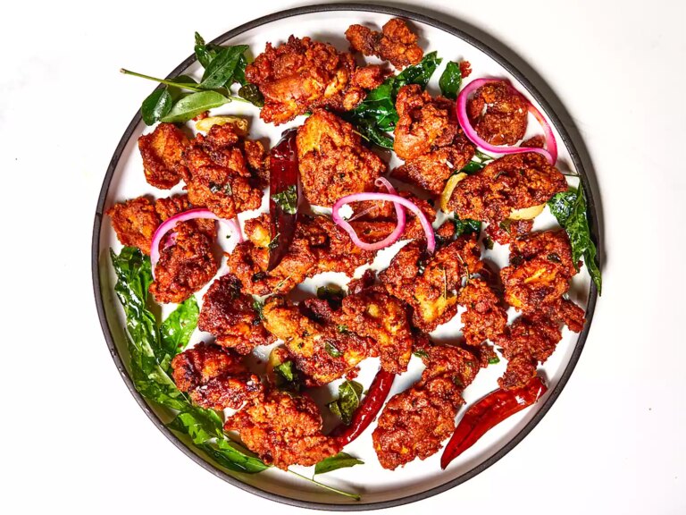 Overhead view of indian spiced chicken 65 on round plate with peppers