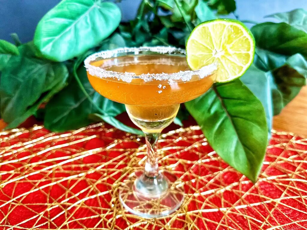 Margarita glass with guava margarita with lime slice on red and gold mat