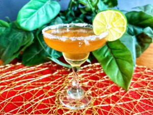 Margarita glass with guava margarita with lime slice on red and gold mat
