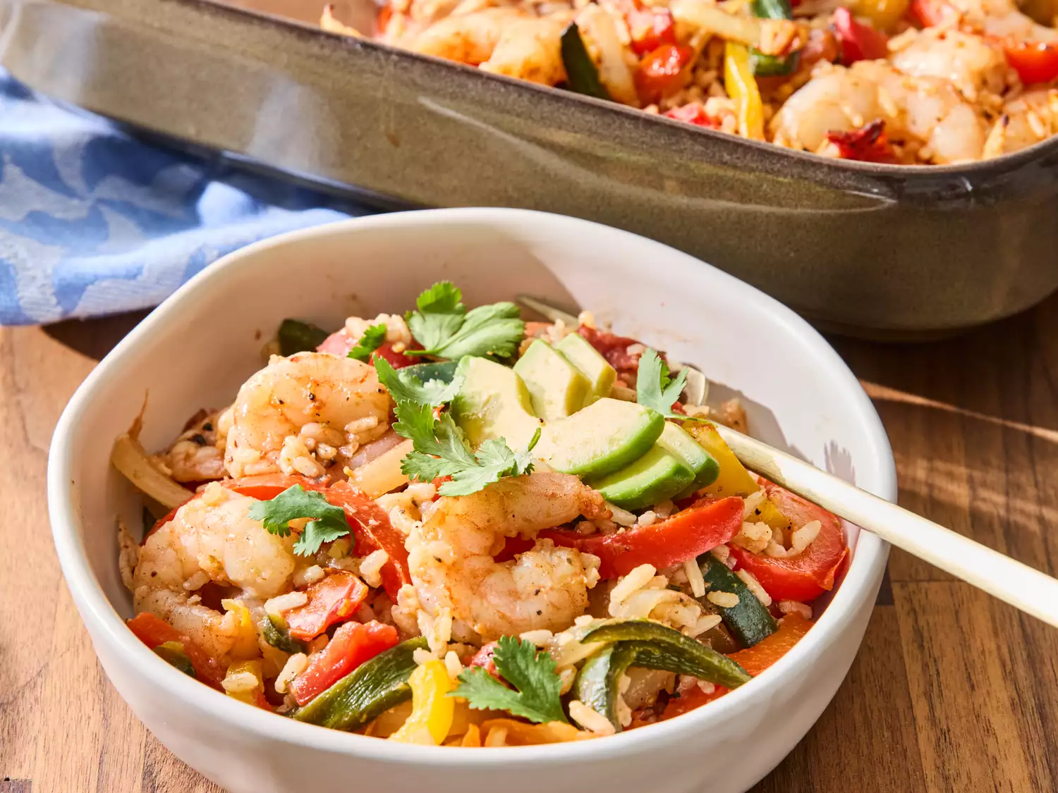 Bowl of shrimp fajita rice casserole with vegetables garnished with avocado slices and cilantro