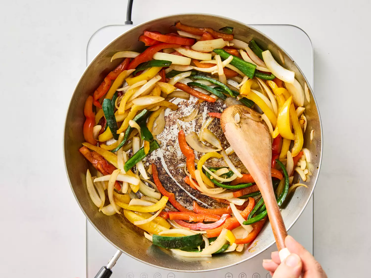 Stir-frying sliced bell peppers and onions in a pan