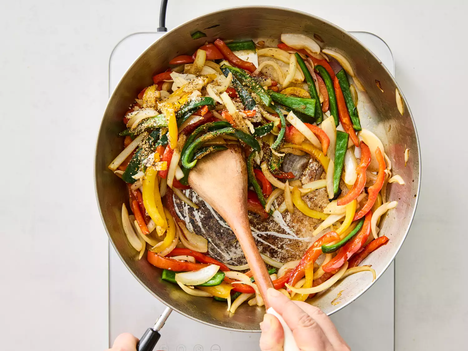 Seasoned peppers and onions being cooked in a skillet