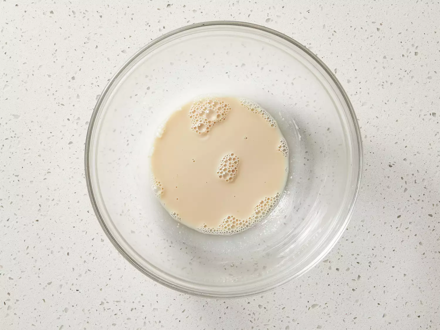 Warm water and yeast stirred together in a mixing bowl.