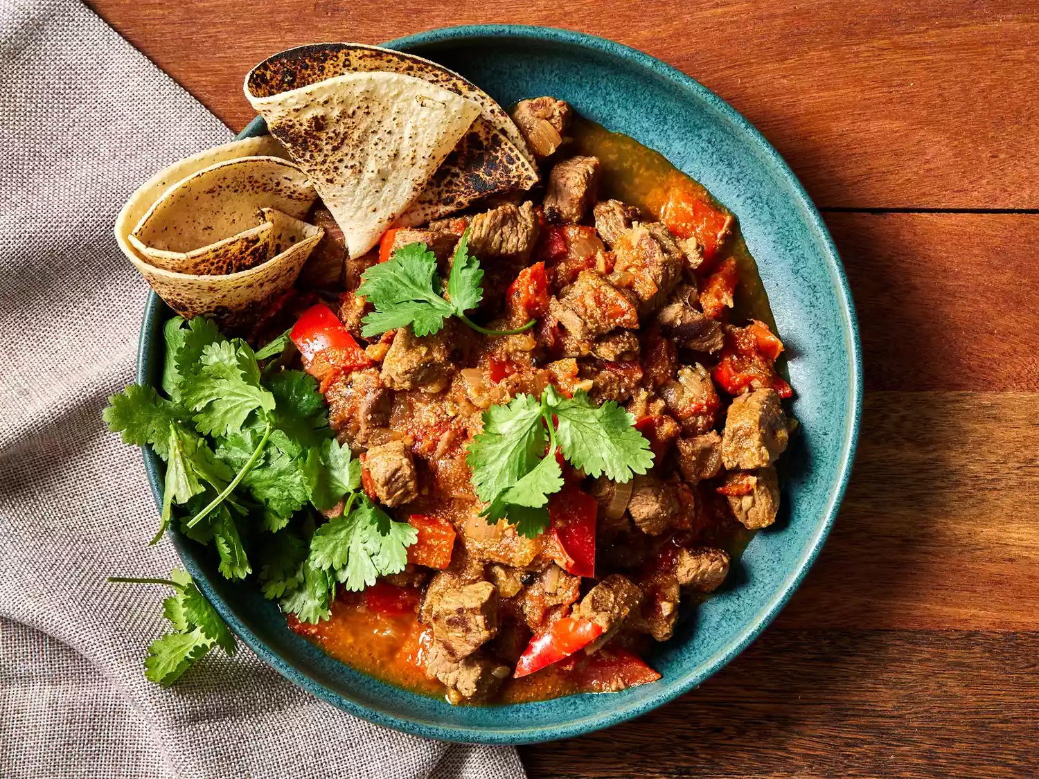 A bowl of south texas carne guisada garnished with cilantro and served with tortillas