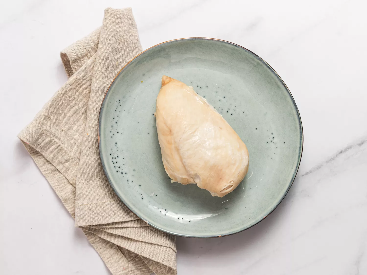 Cooked chicken breast on a green plate with a napkin.