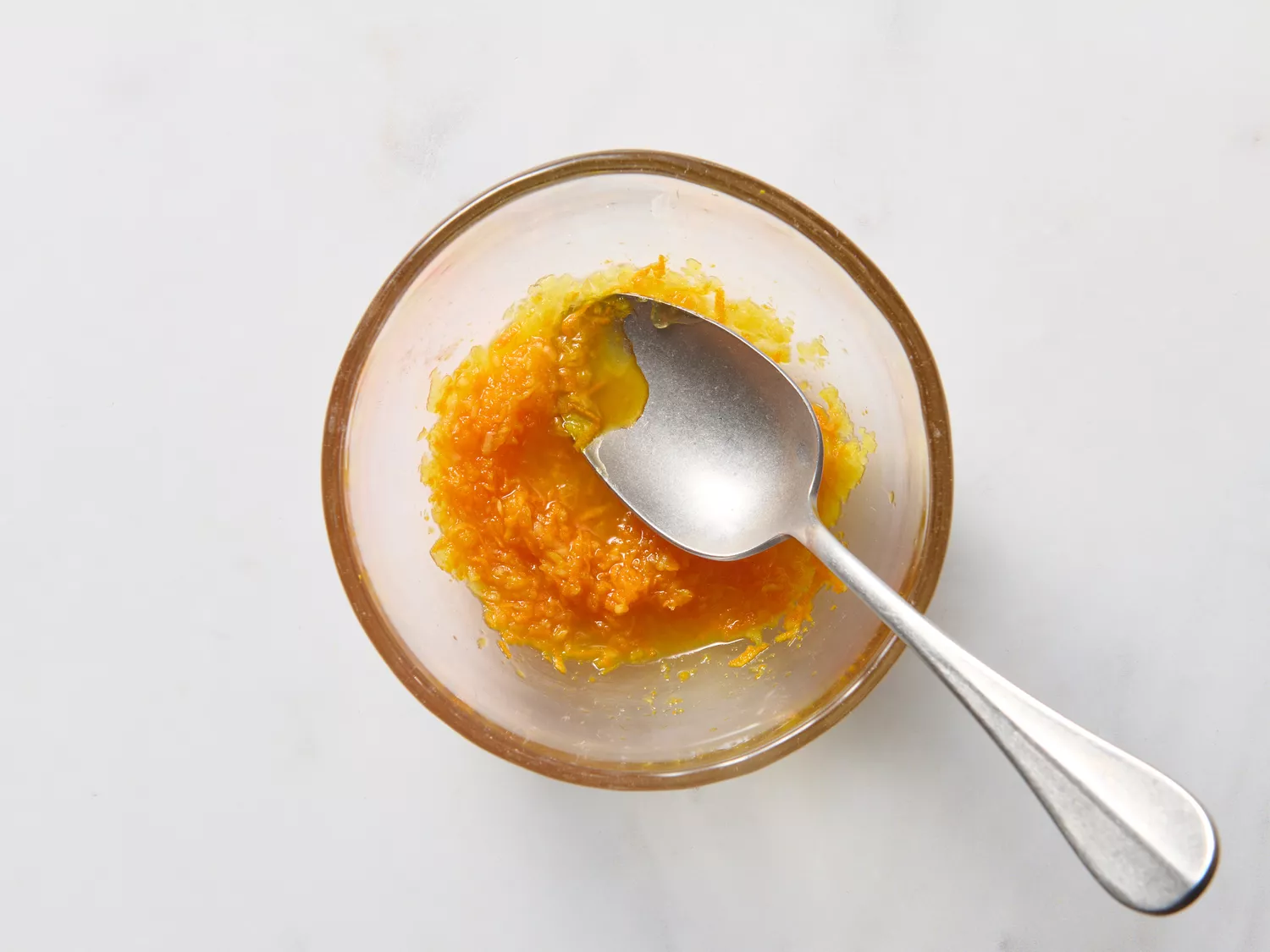 Bowl with mashed turmeric and ginger mixture with a spoon.