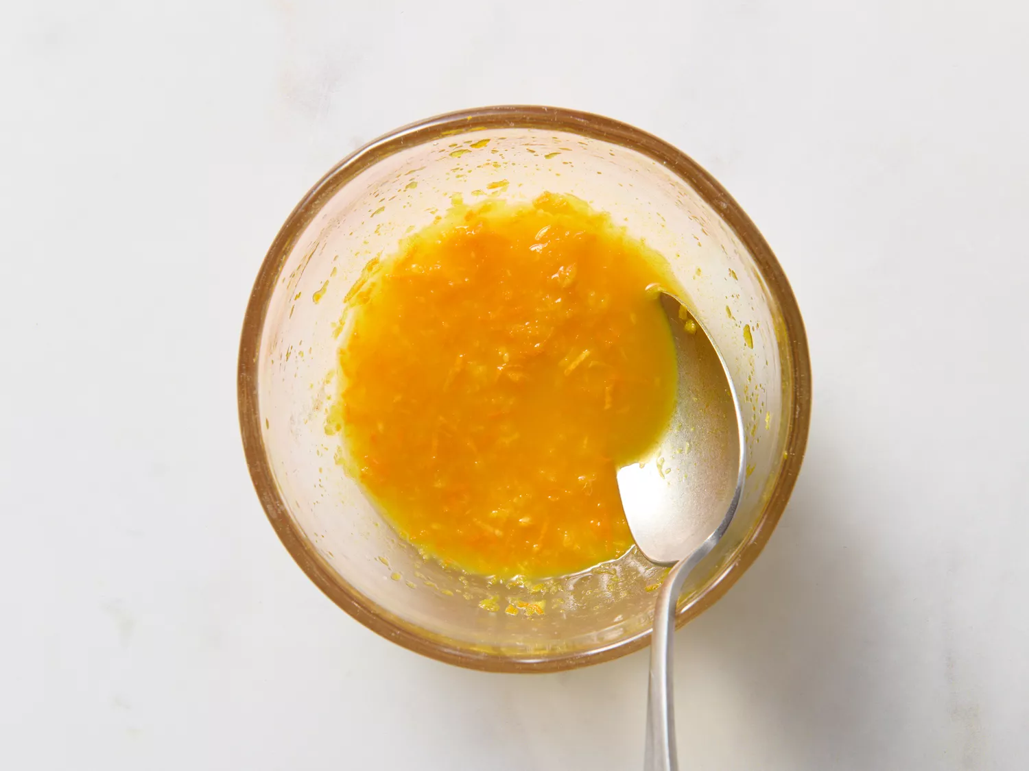 Bowl with mashed turmeric and ginger mixture, partially mixed.