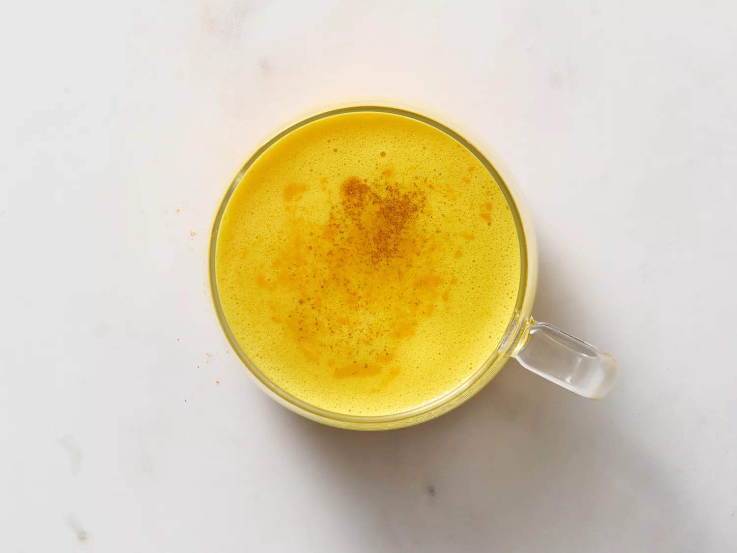 Top-down view of turmeric latte in a glass mug with cinnamon.