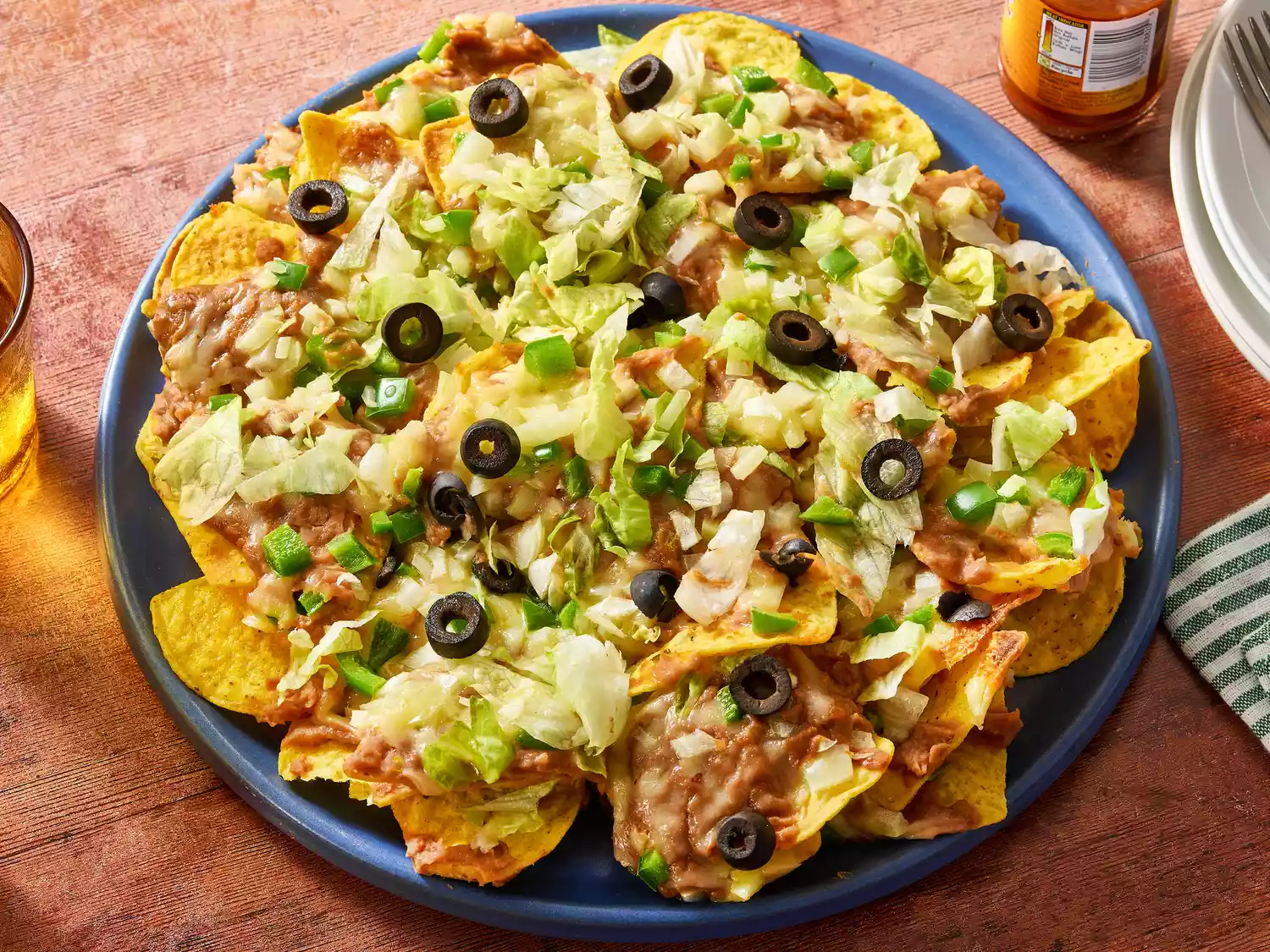 Loaded nachos with beans, cheese, lettuce, and olives.