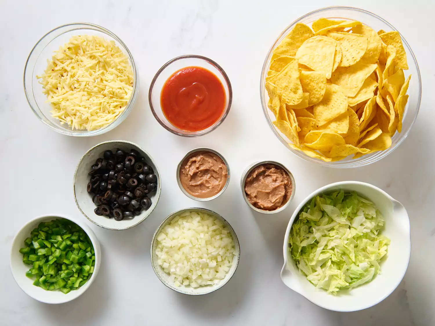 Ingredients for nachos arranged in small bowls.
