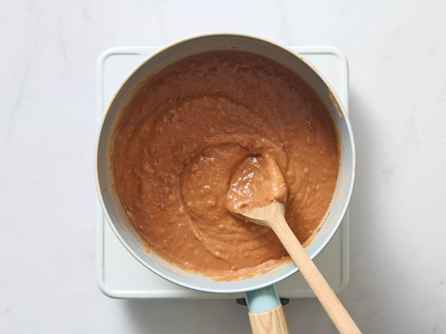 Saucepan with refried beans being stirred.
