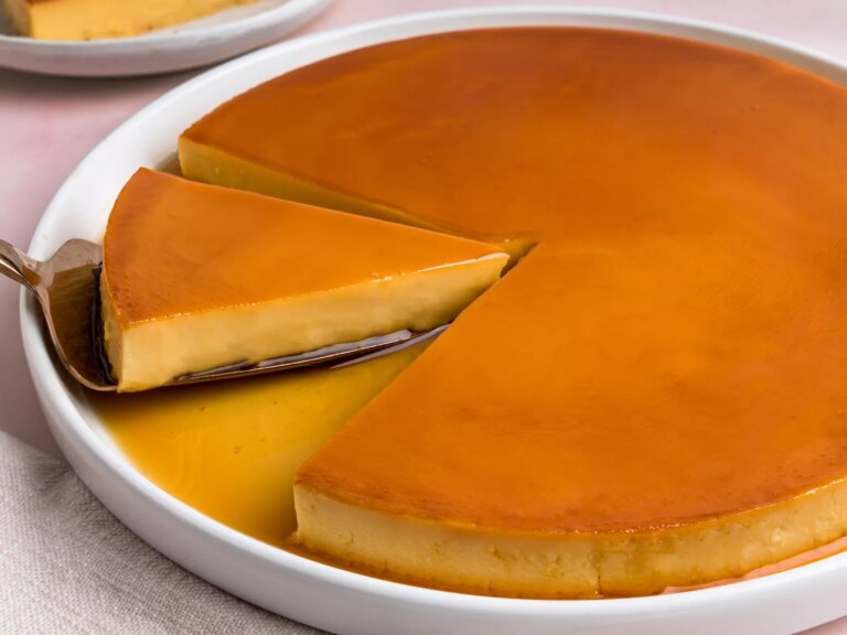 Slice of caramel flan being lifted from a full flan.