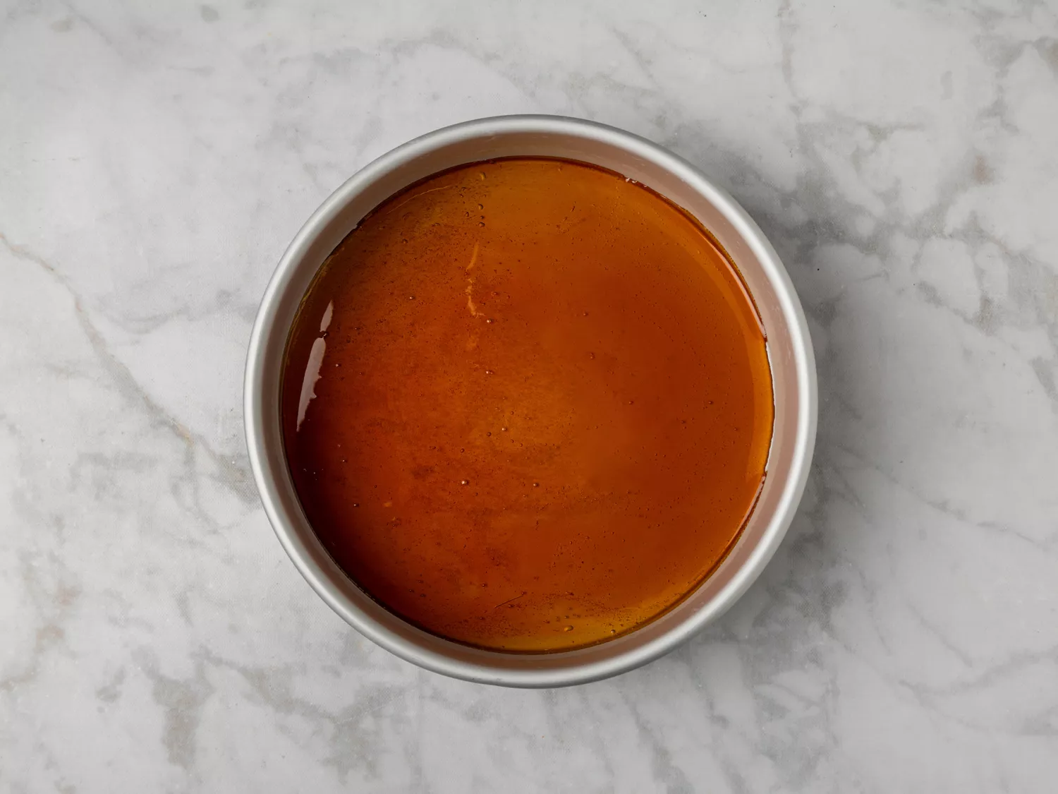 Cooled caramel layer in a round baking pan.