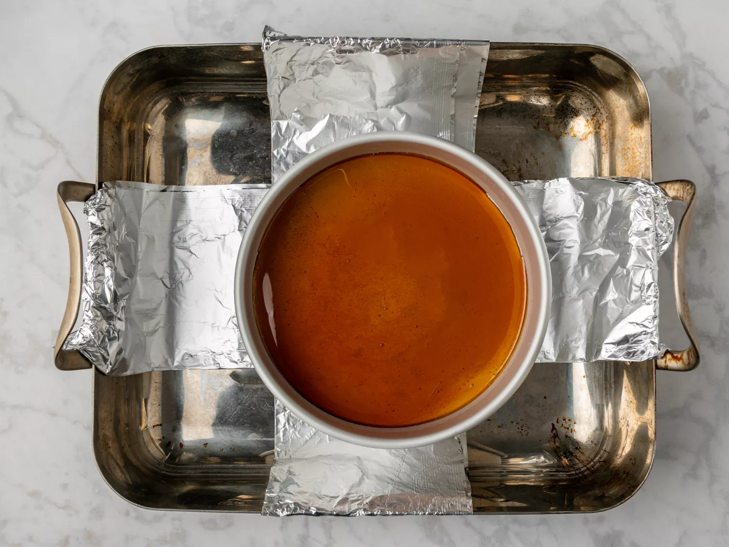 Caramel-coated pan placed in a water bath for baking.
