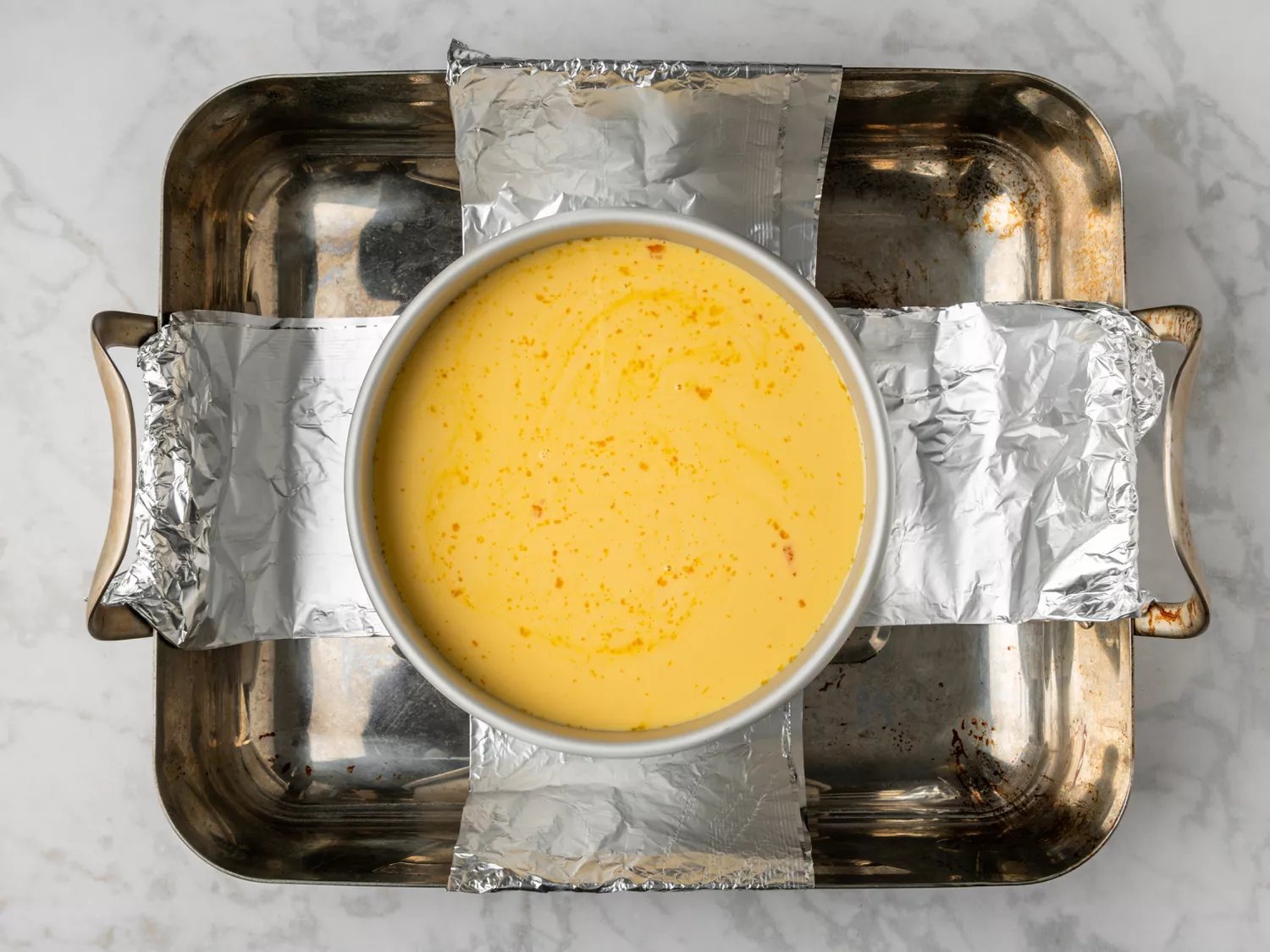 Flan mixture poured into a caramel-lined pan in a water bath.