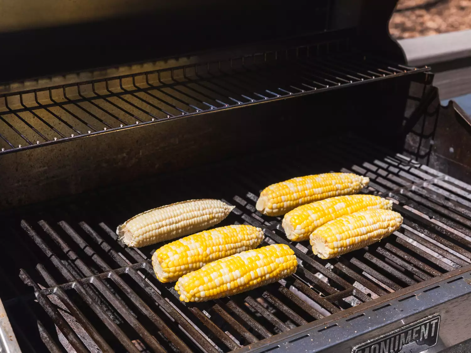Grilled corn on the cob arranged on a barbecue grill.