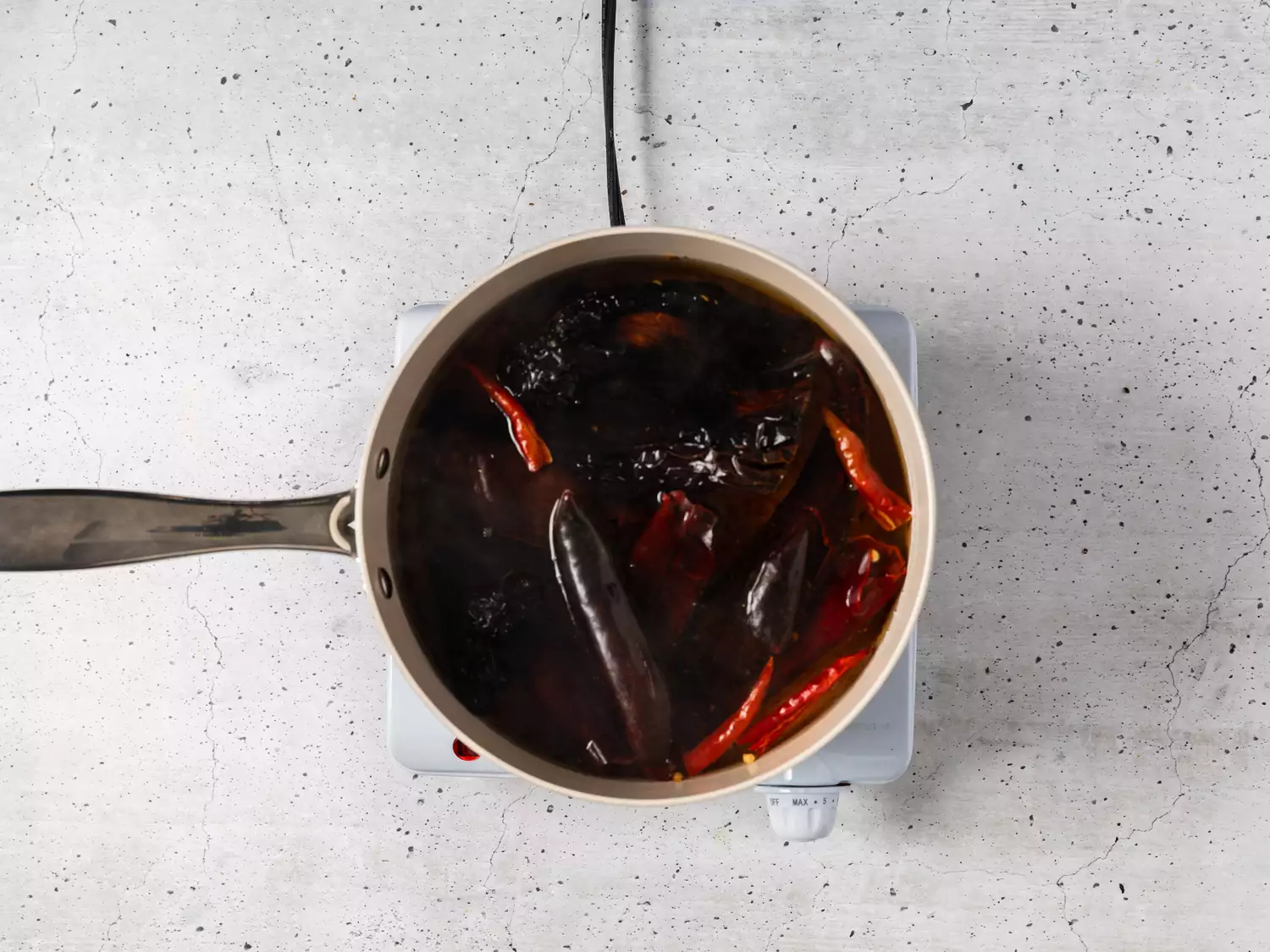 A pot of guajillo, arbol, and ancho chile peppers boiling in water
