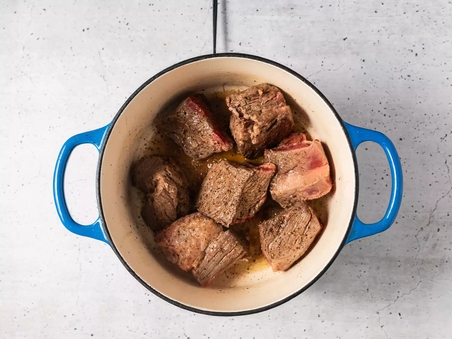 A pot with seared pieces of beef