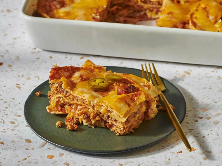 Slice of enchilada casserole on a green plate with fork.