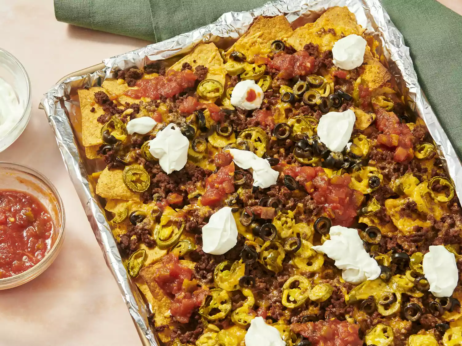 Baked nachos topped with ground beef, cheese, jalapeños, and sour cream.