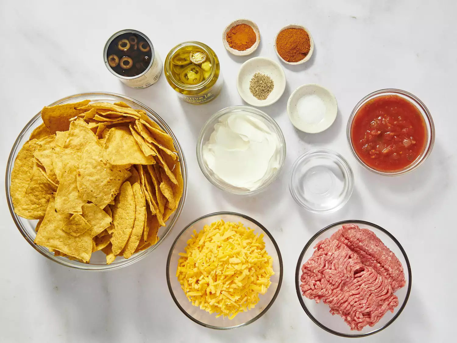 Ingredients for nachos, including chips, cheese, beef, and seasonings.