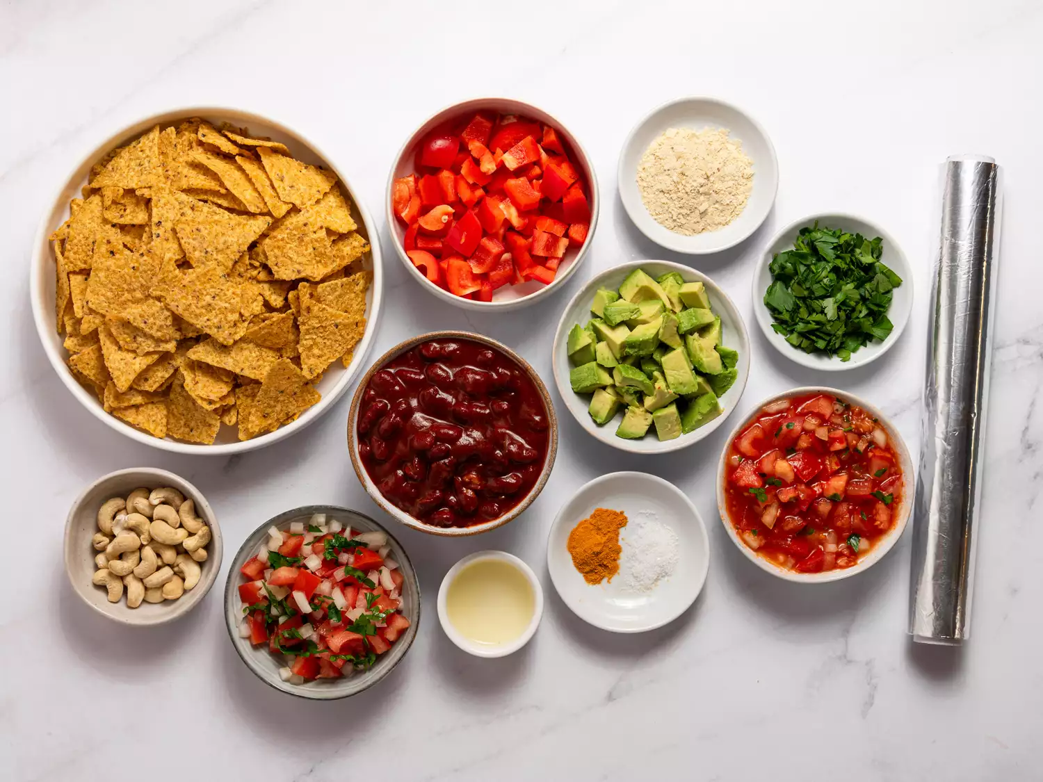 Ingredients for nachos arranged in small bowls.