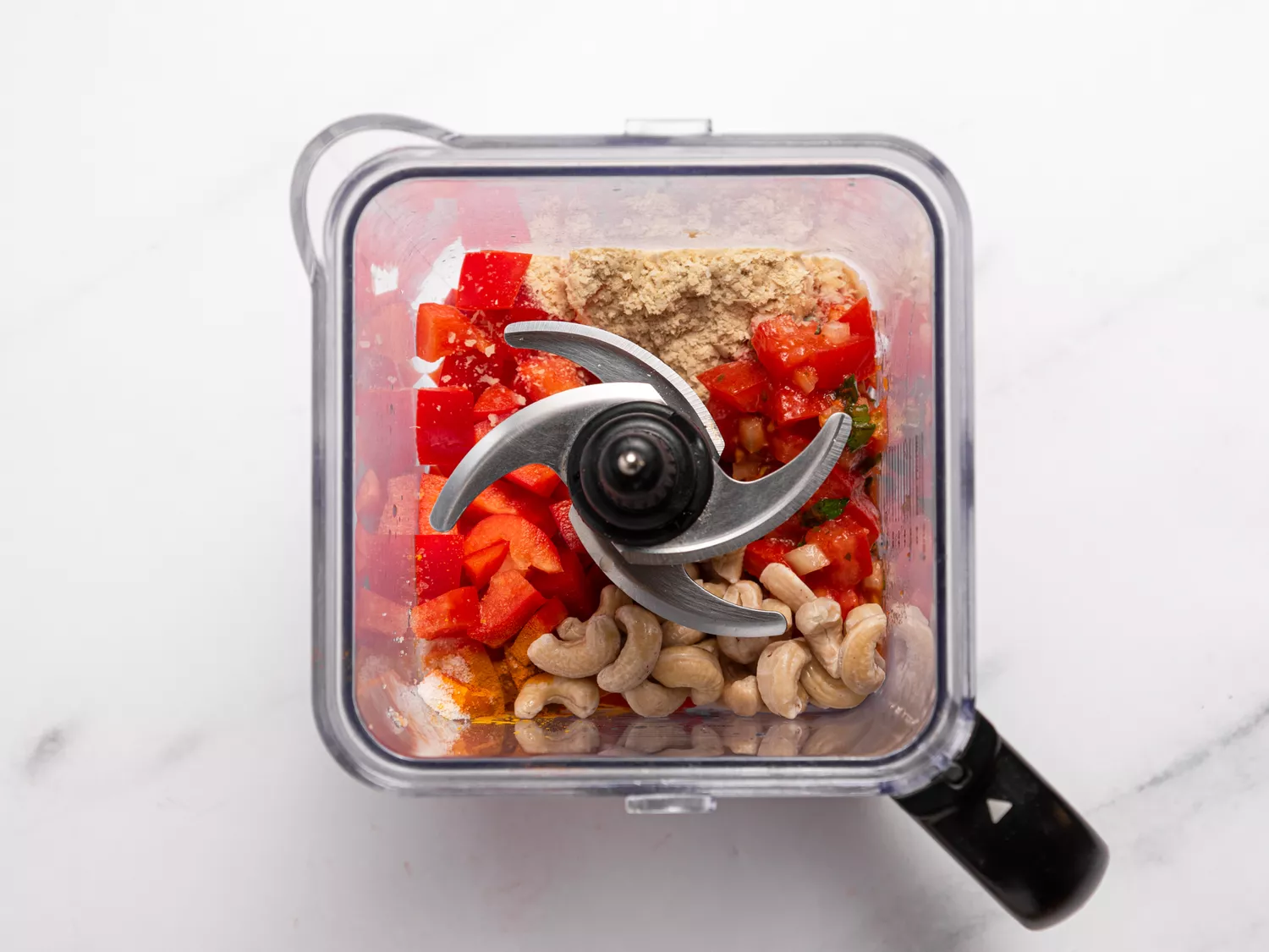 Blender filled with red peppers, cashews, and seasonings.