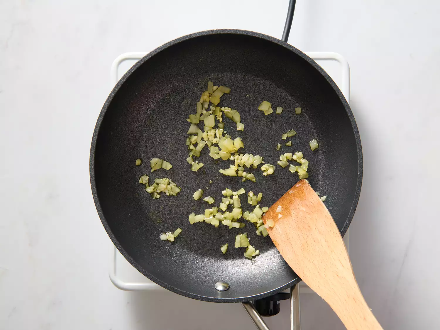 A pan with chopped onion and garlic cooking in vegan butter