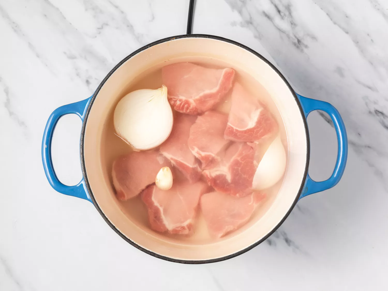 Pork cooking in a pot with onions. 