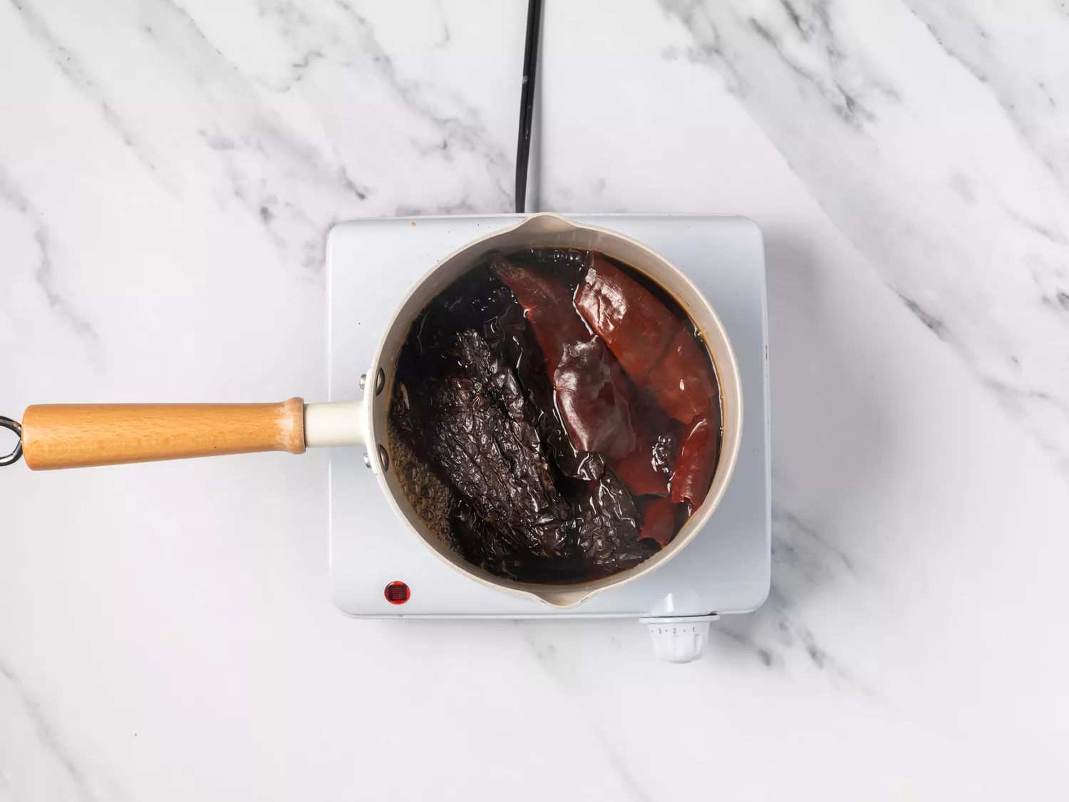 Dried chiles cooking in a saucepan. 