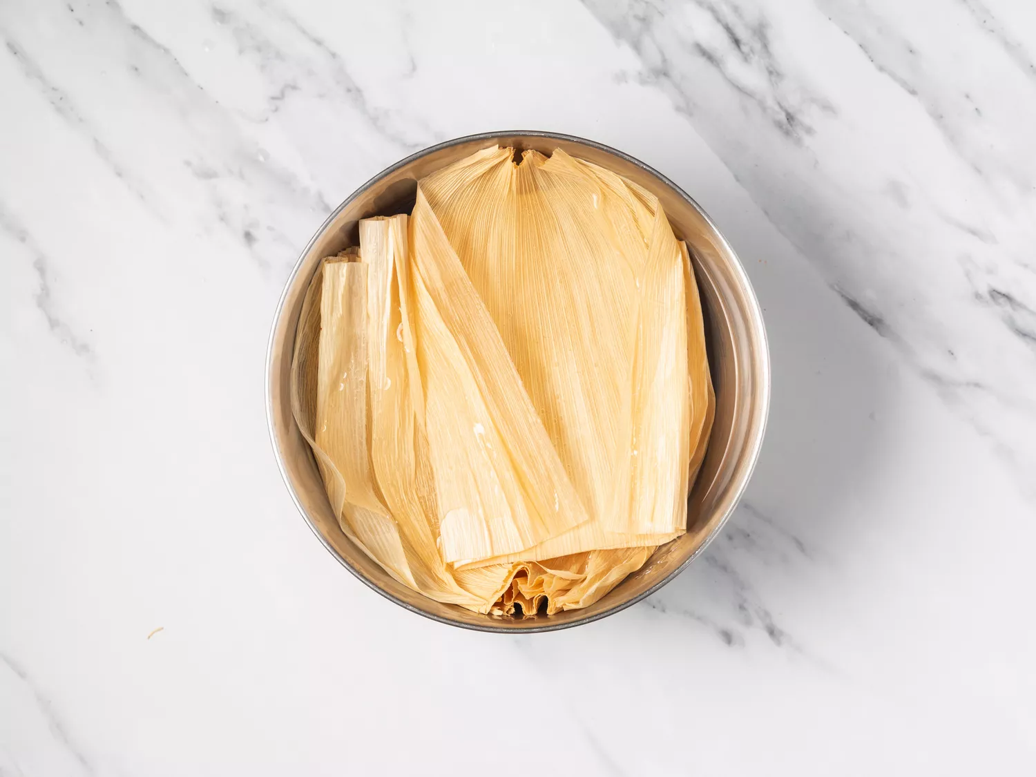 Corn husks soaking in a bowl of water.