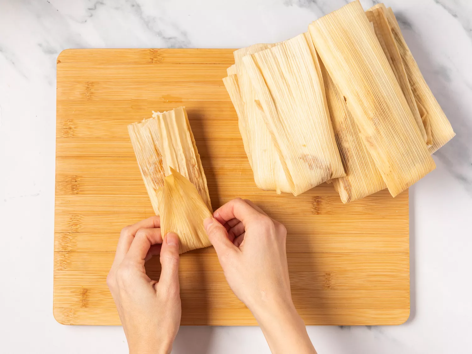 A person folding a tamale.