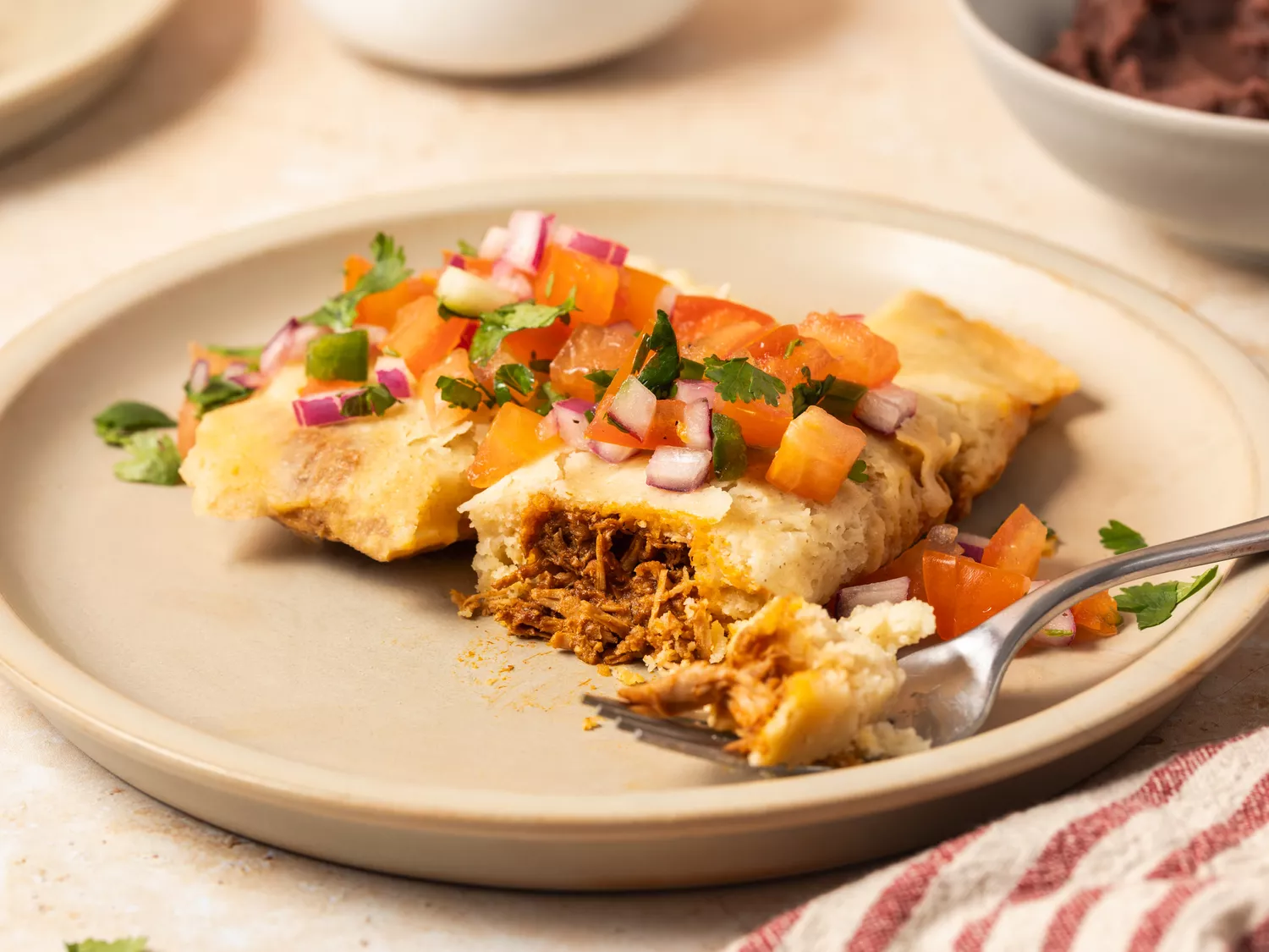 Tamales served on a plate topped with salsa.