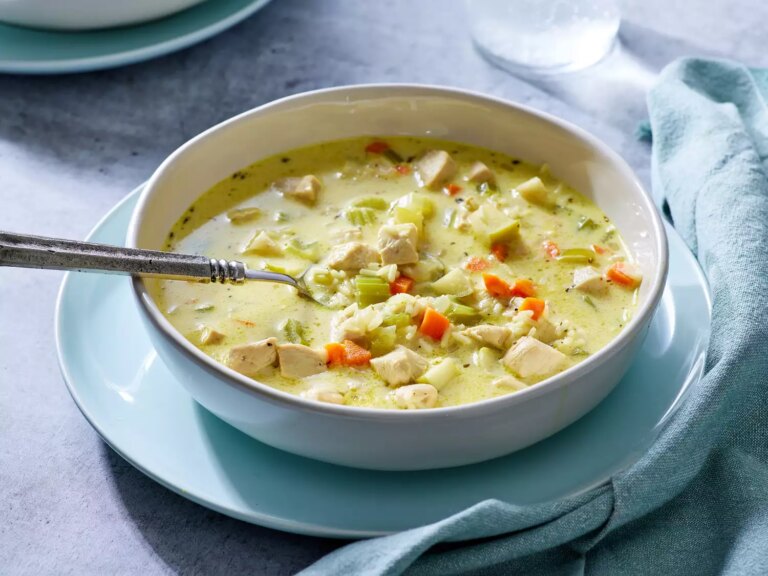 A bowl of creamy mulligatawny soup with chicken, celery, and carrots