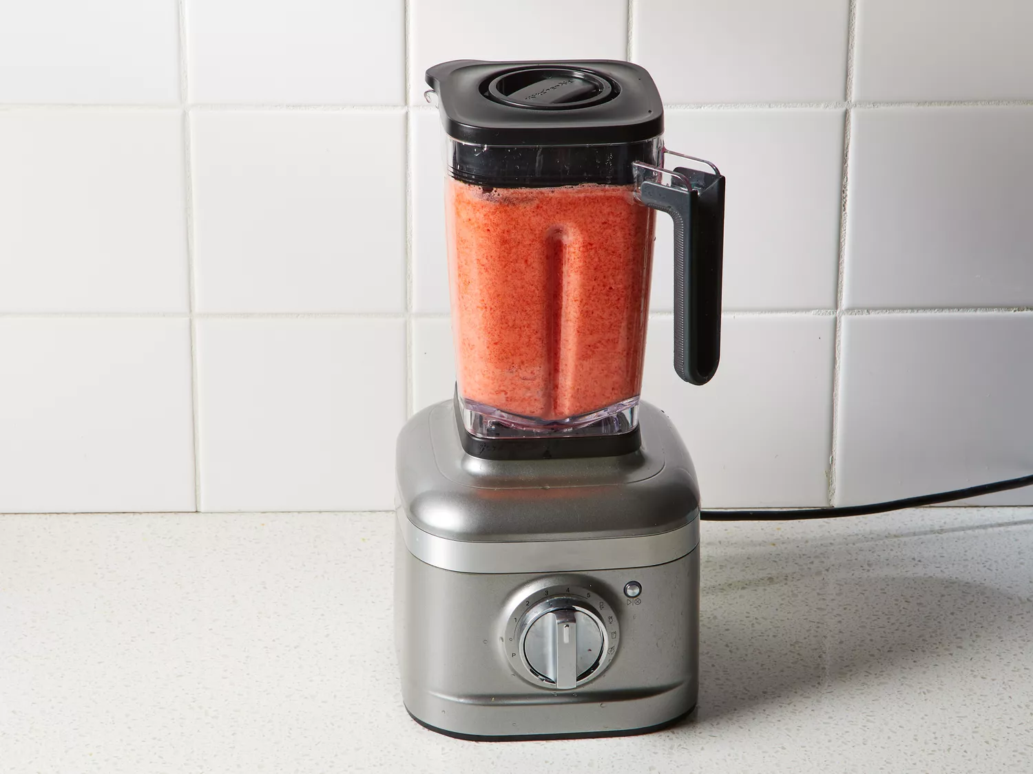 A blender with blended strawberry-sugar mixture
