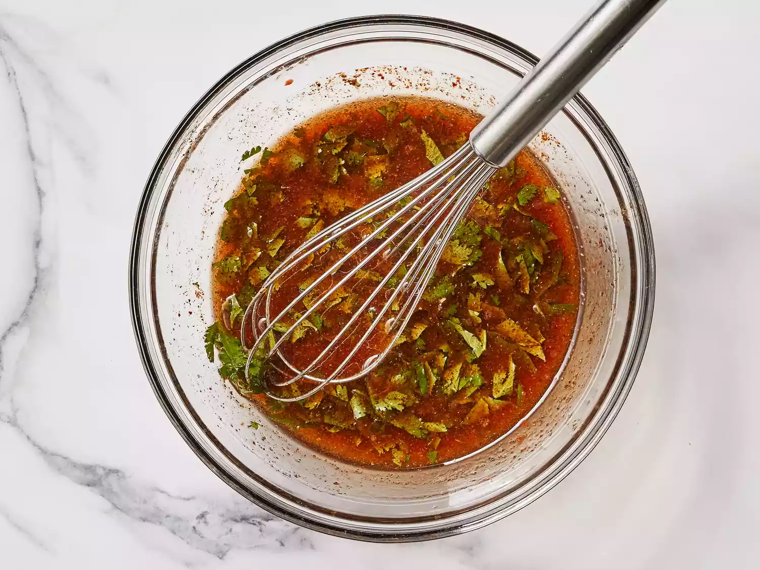A bowl of vinaigrette with a whisk