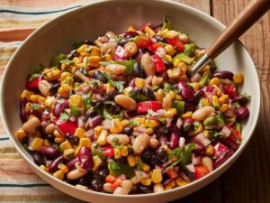 A serving bowl of mexican bean salad with a serving spoon