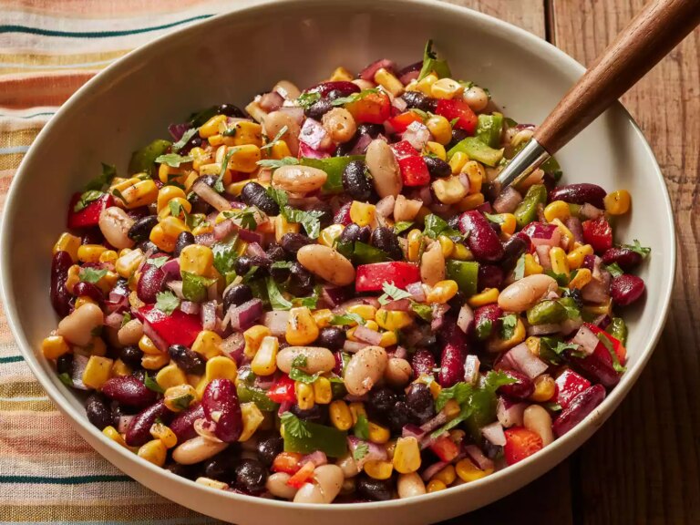 A serving bowl of mexican bean salad with a serving spoon